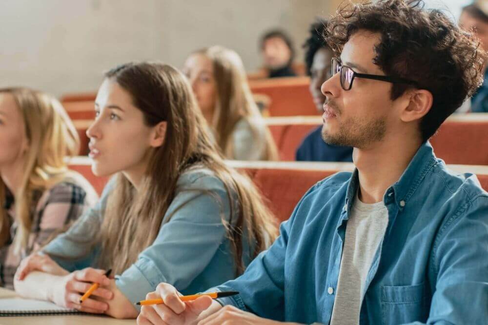 Mehrere Studente sitzen in einem Vorlesungssaal und nehmen am Unterricht teil. | Studienorte Österreich